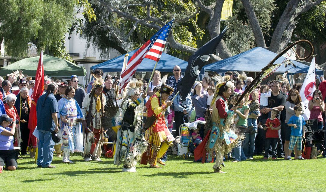Dancers, holding flags, during a performance at an outdoor event.