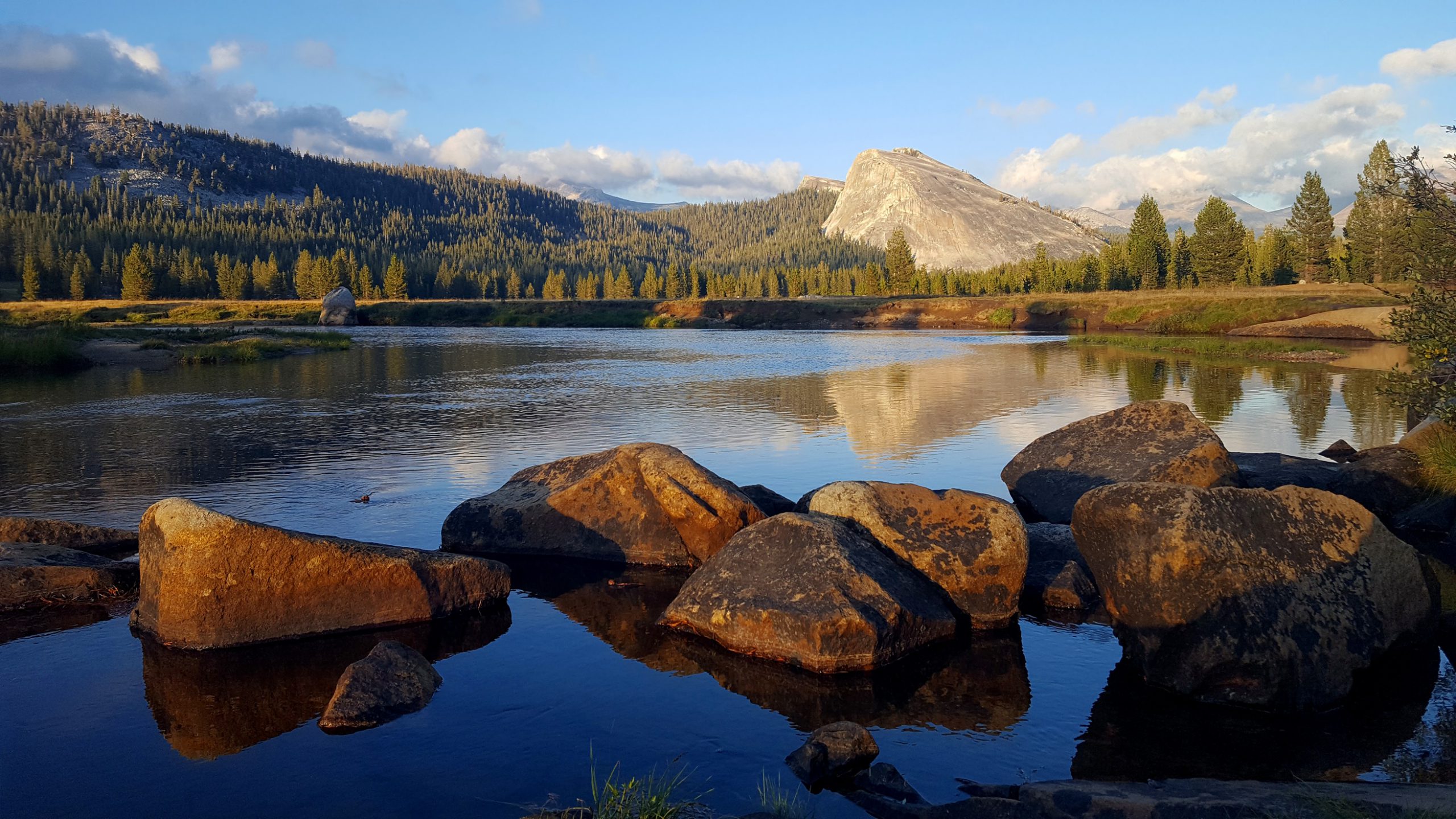 A panoramic vista of mountains, with a pond in the foreground.