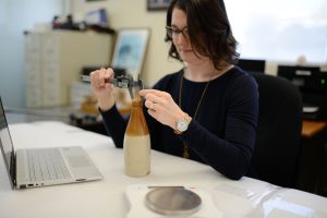 Molly measuring a bottle at an indoor desk