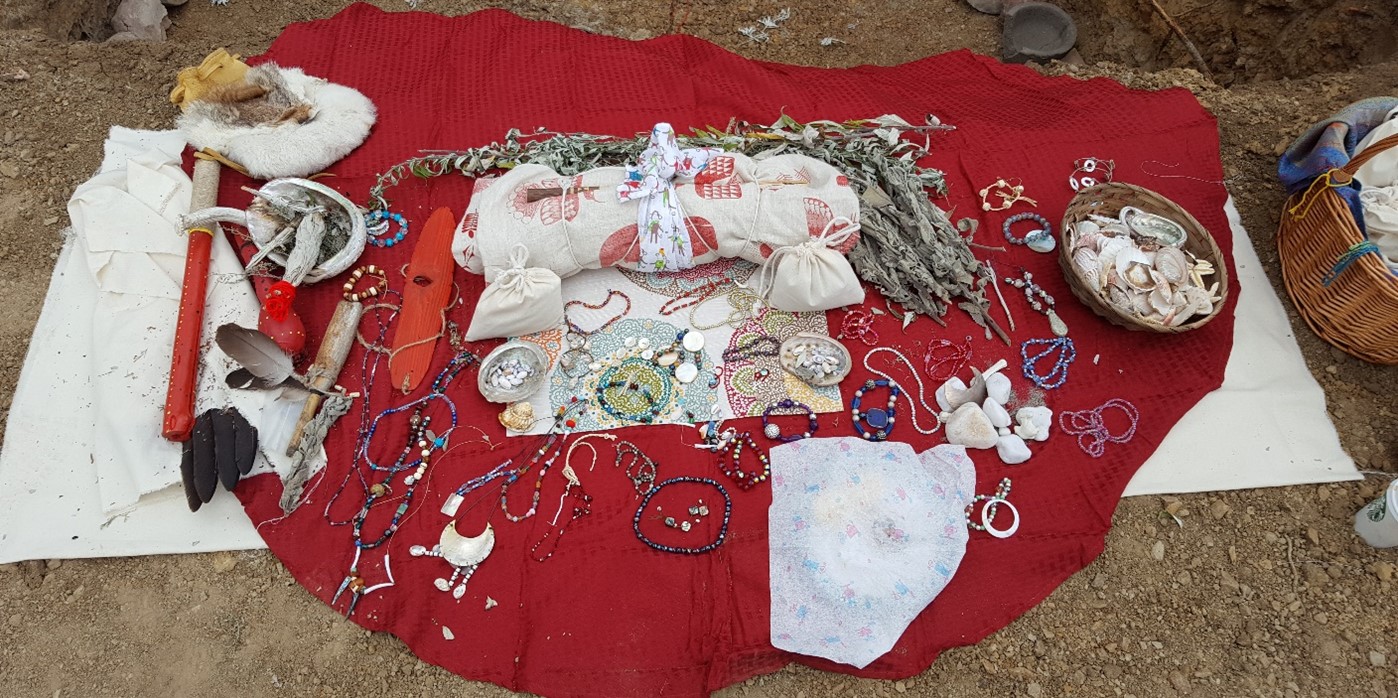 A collection of Indigenous artifacts on a red blanket.