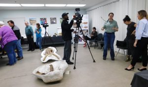 Indoor fossil event with photographer and crowd
