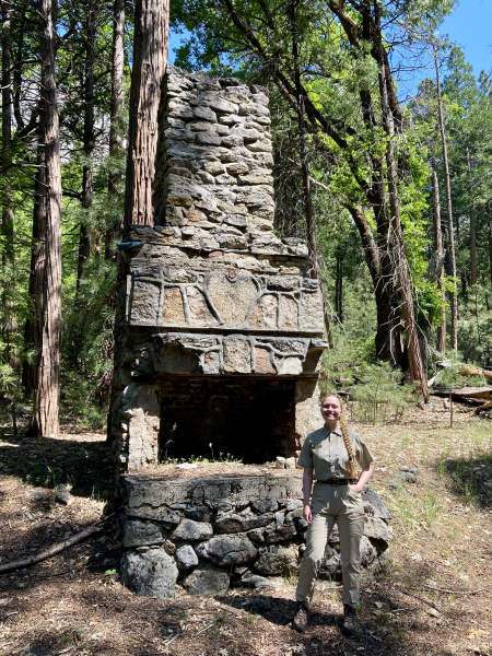 Grace Eriksen, recipient of the 2023 Sherri Gust Memorial Scholarship, standing next to a historical fireplace.