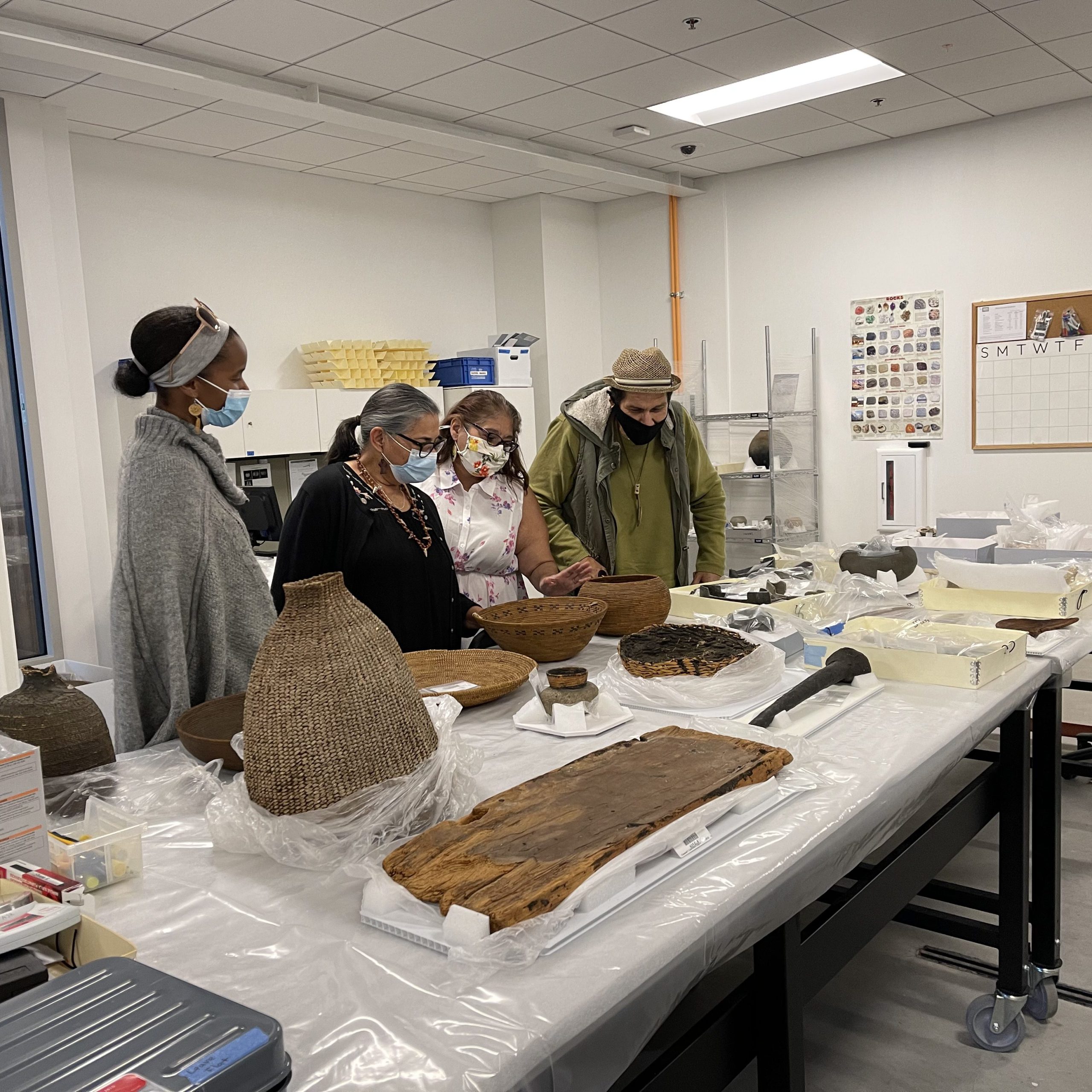 Four people examining ancestral and cultural artifacts.