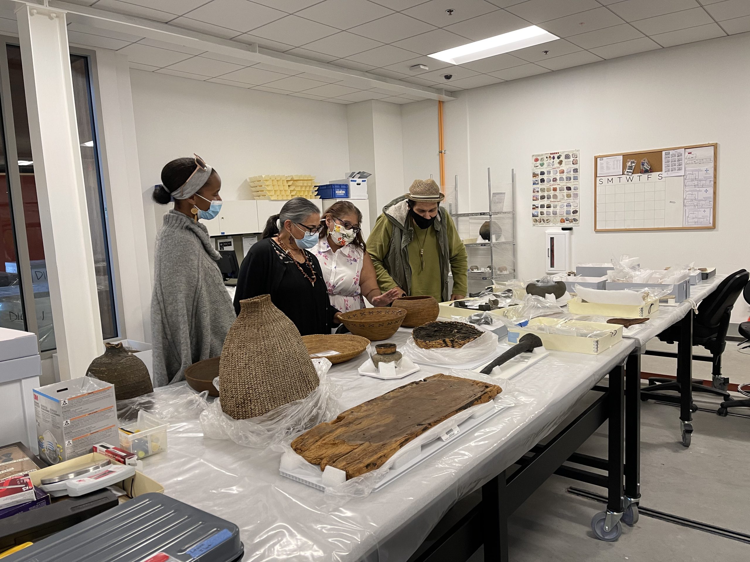 Four people examining Indigenous ancestral artifacts.