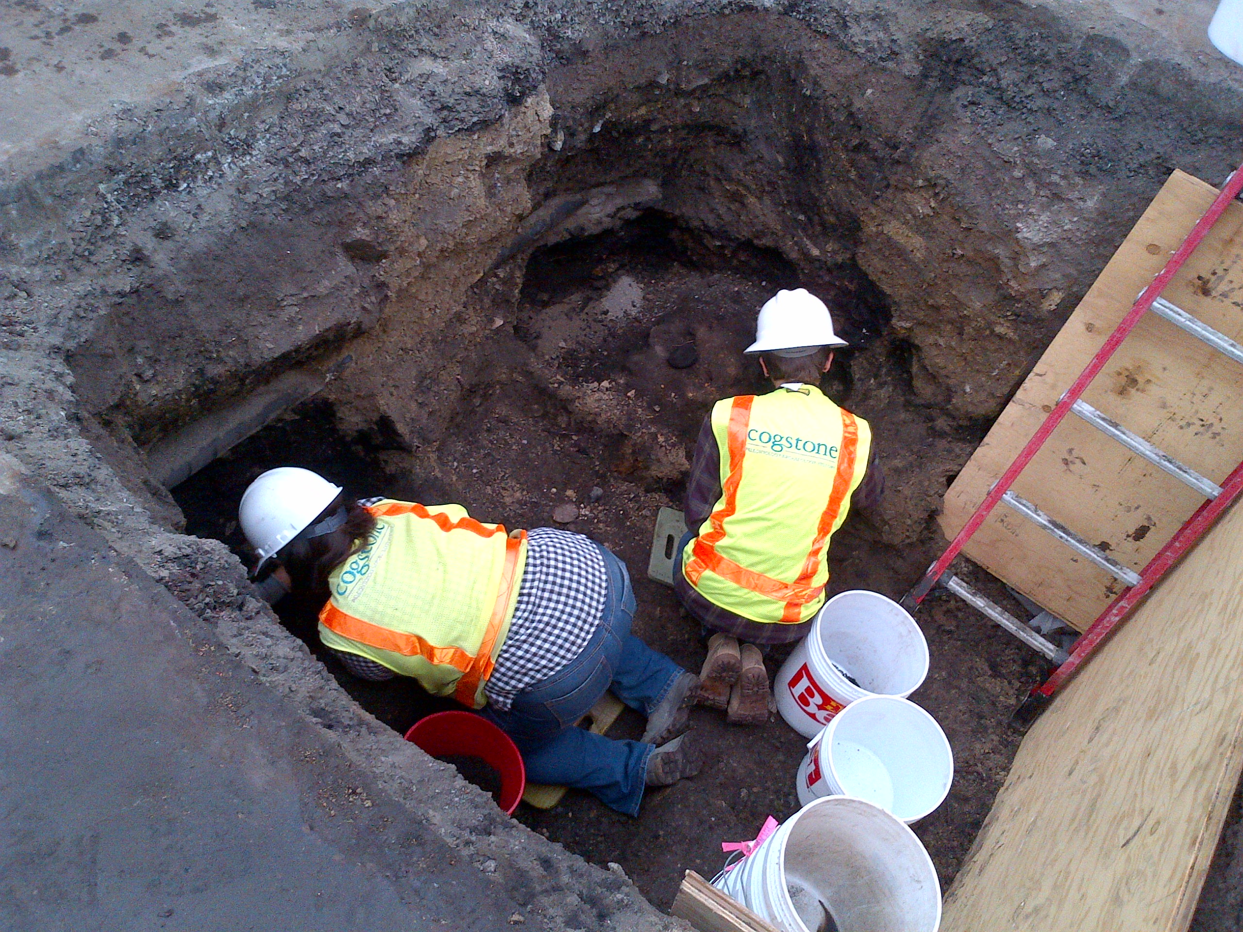 Two archeologists during an excavation, several feet deep in the ground.