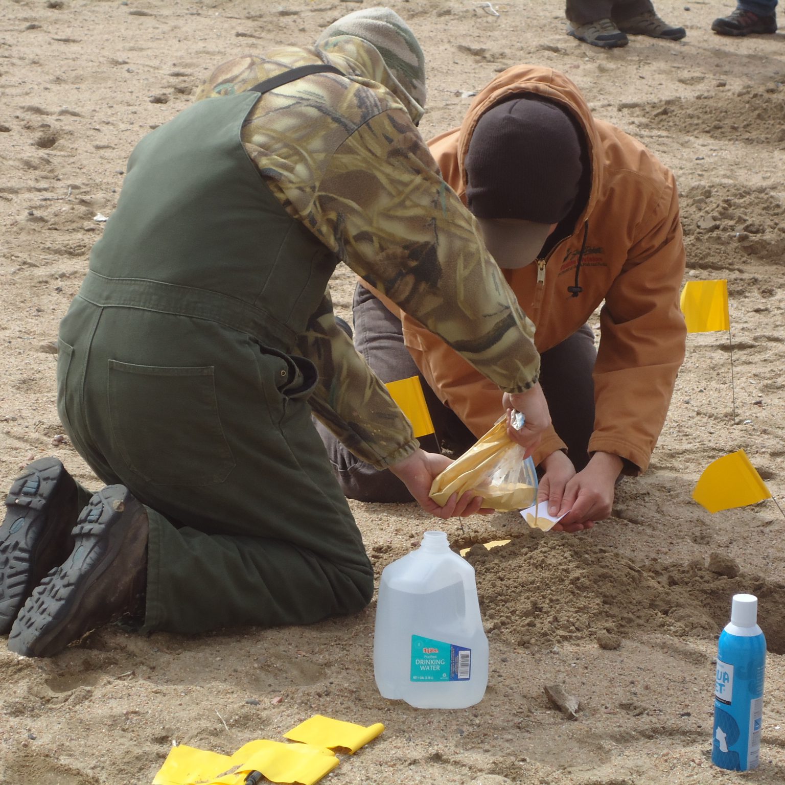 Two people at an outdoor site, pouring traxtone powder