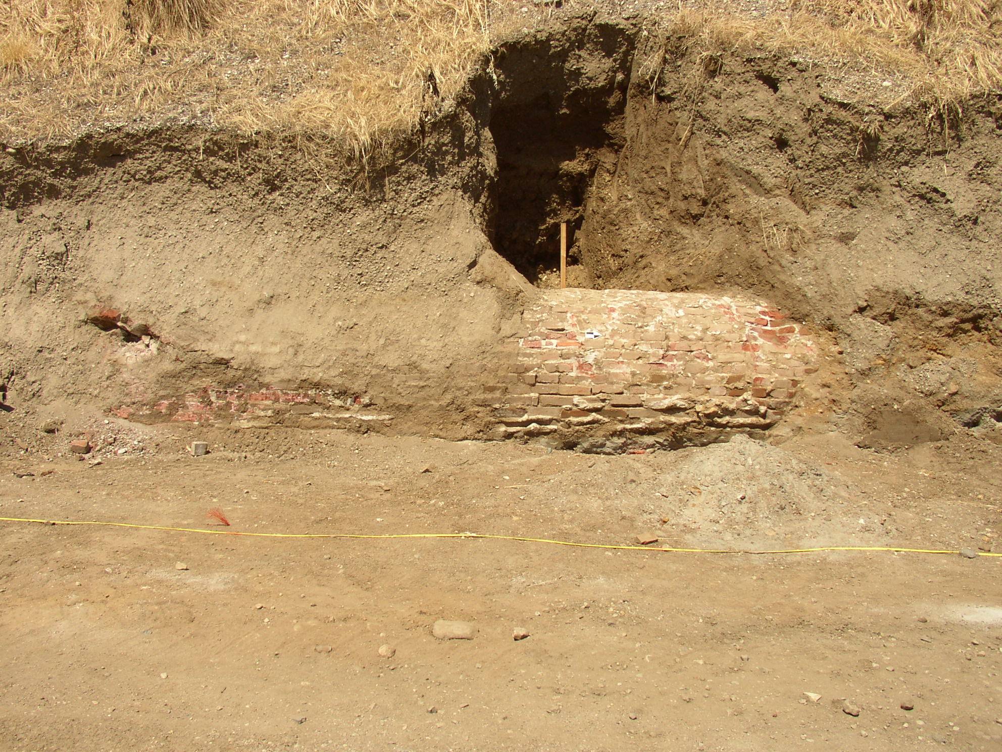An marked-off archeological work site within a dry mound of soil.
